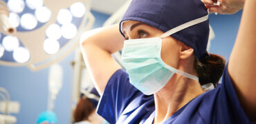 Side view of young female surgeon tying her surgical mask